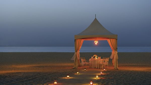 Lantern-lit beach dinner beneath the white gazebo
