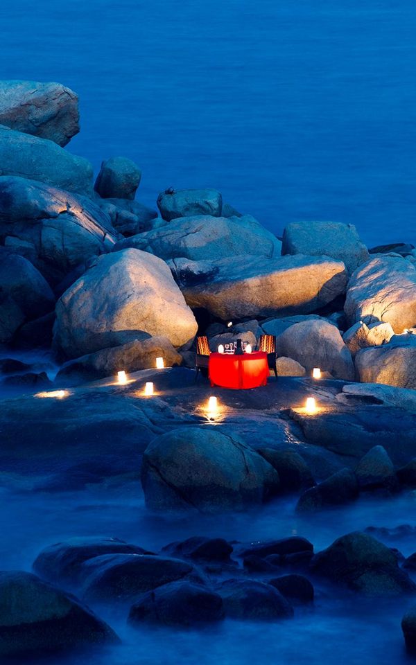Lantern and candle-lit dinner on a rocky shore