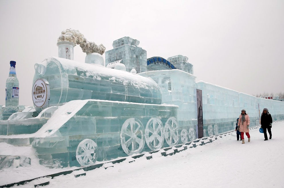 Visitors walk past a train-shaped ice sculpture 