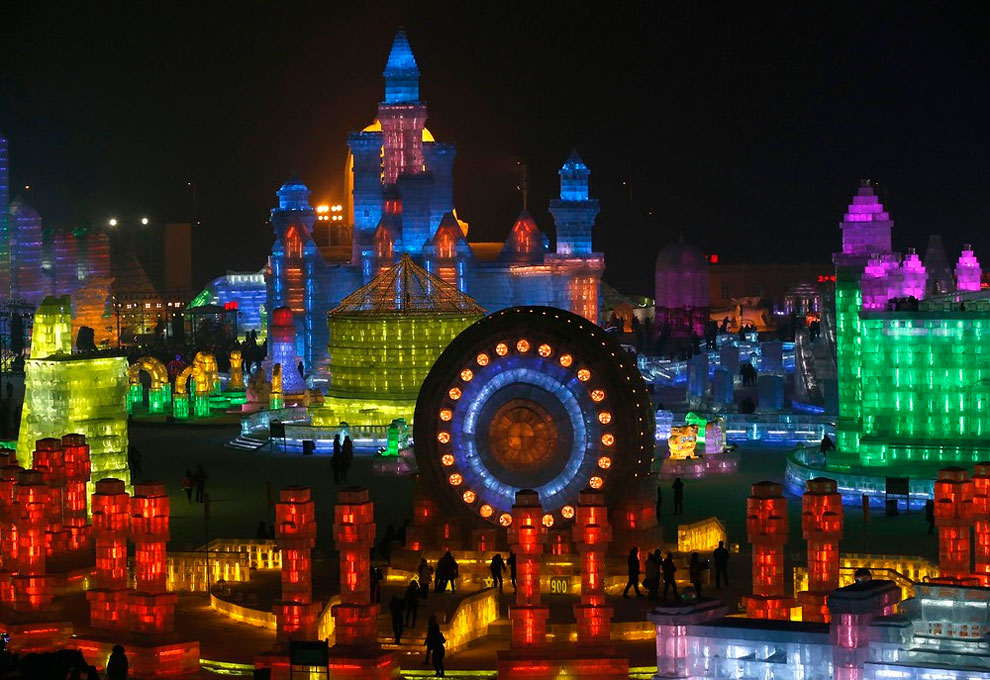 People visit ice sculptures illuminated by colored lights during a trial operation