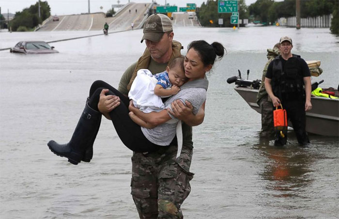 Houston Police SWAT Officer Daryl Hudeck Carries Catherine Pham And Her 13-Month-Old Son Aiden After Rescuing Them From Their Home Surrounded By Floodwaters From Tropical Storm Harvey In Huston