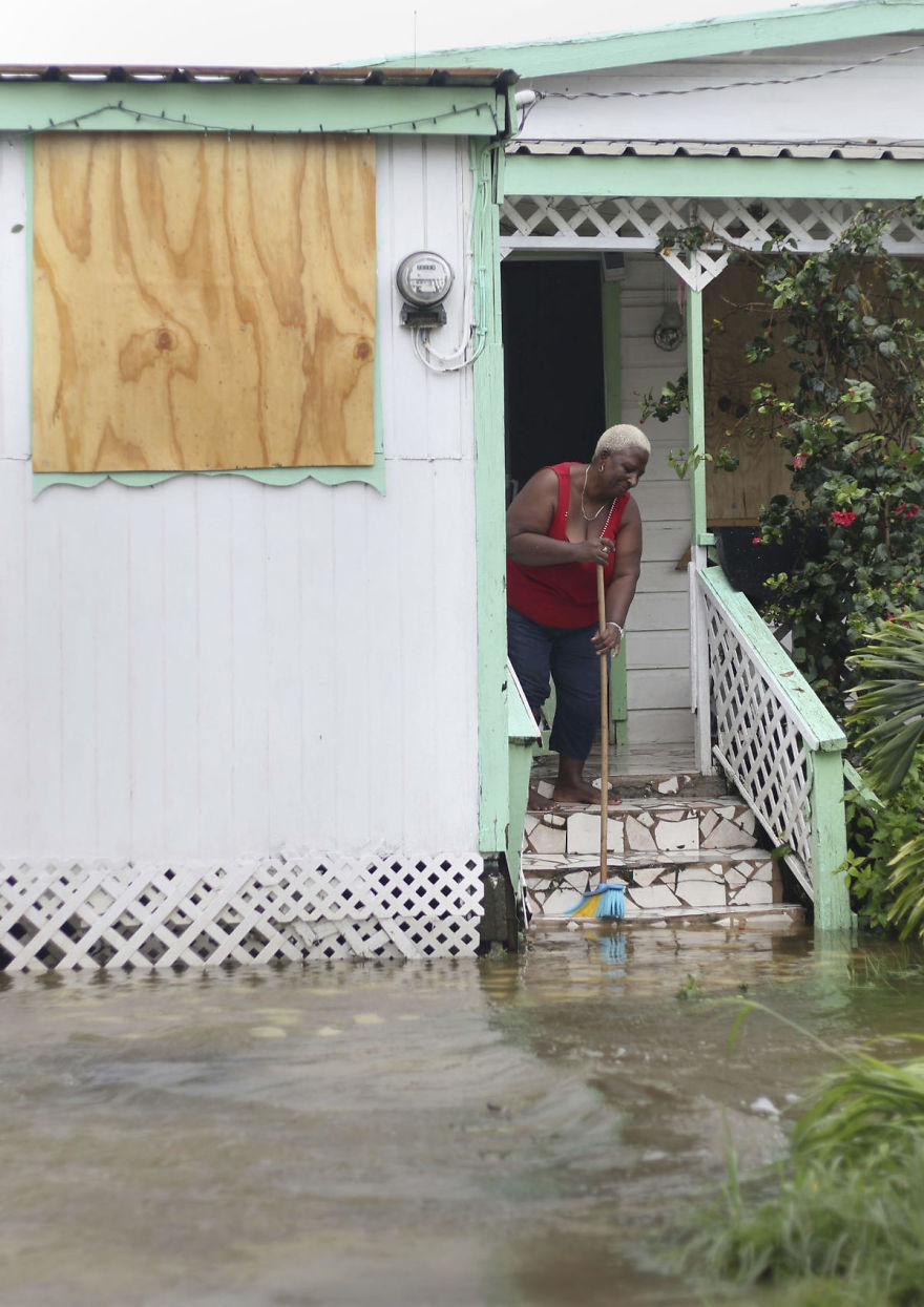 A Woman Pushes Out Floodwaters On Her Property After The Passing Of Hurricane Irma, In St. John's, Antigua