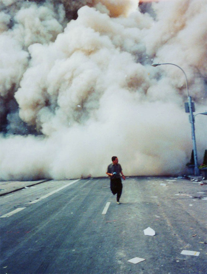 A Lone Man Runs Down Broadway As A Smoke And Dust Cloud Comes Up The Street From The Collapsing World Trade Center Buildings In New York September 11, 2001