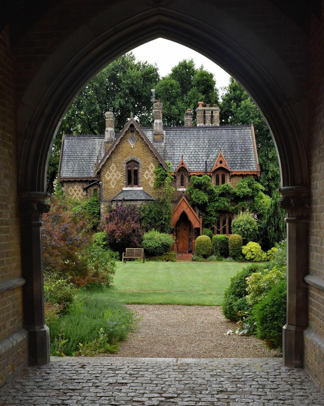 19th Century Victorian Gothic Cottage Framed By The Arch Of The Gatehouse At Holly Village, Highgate, North London, UK