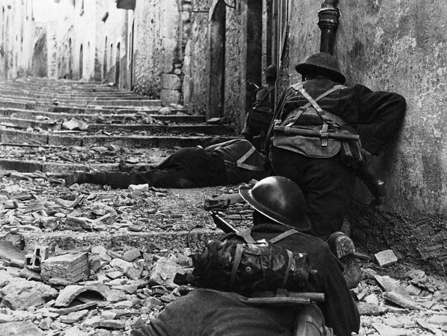 Over The Body Of A Dead Comrade, Canadian Infantrymen Advance Cautiously Up A Narrow Lane In Campochiaro, Italy On November 11, 1943