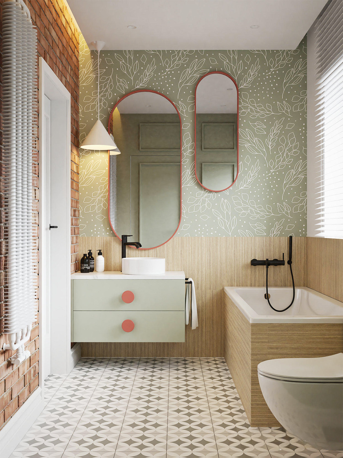 Racetrack-shaped bathroom mirrors place contrasting coral accents onto sage green wallpaper. Coral hardware continues the warming accent onto a pale green vanity unit.