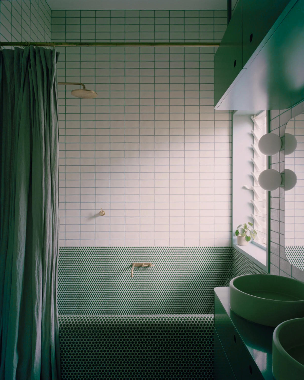 Green mosaic tiles smoothly wrap around this built-in bathtub to create a bespoke finish.