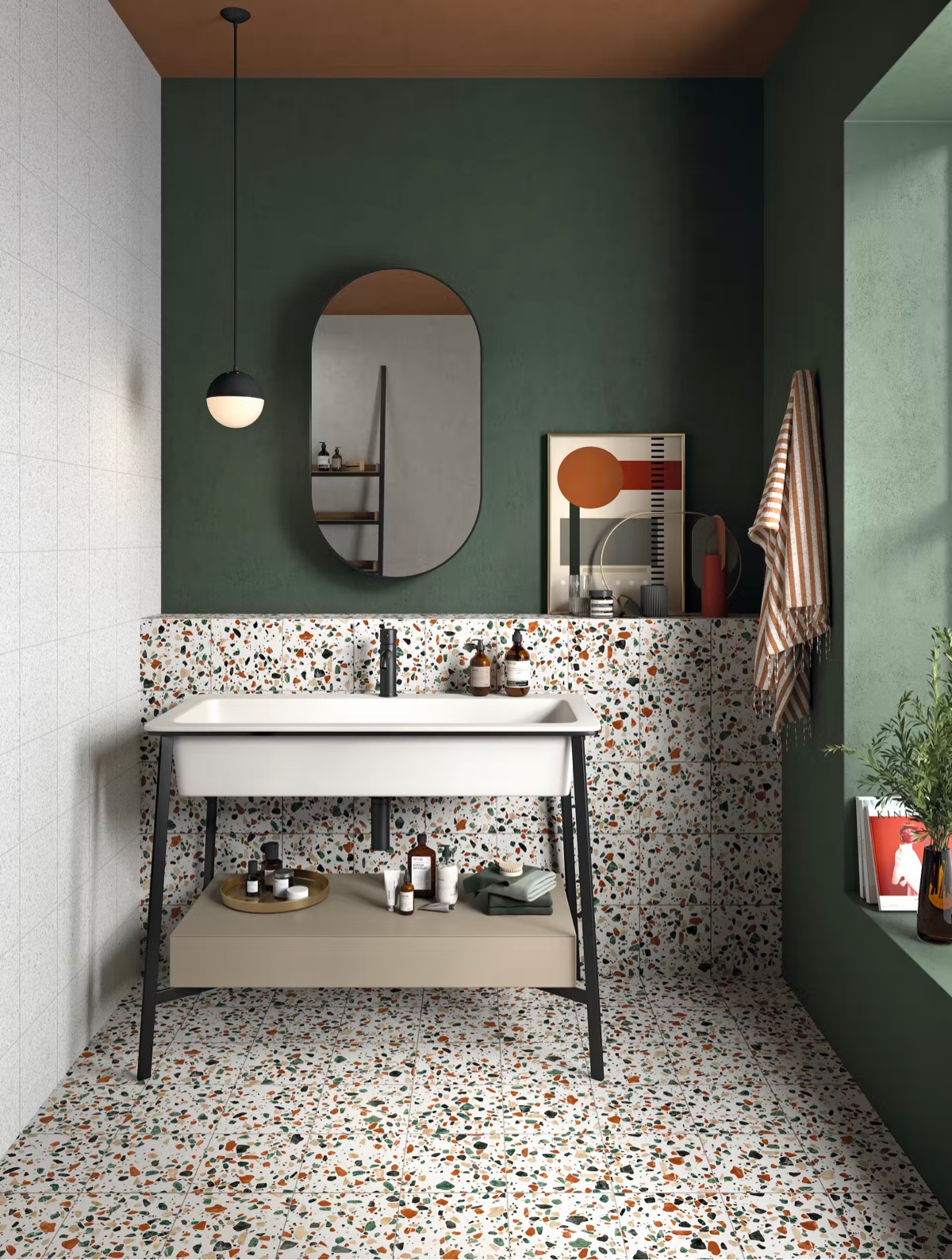 Terrazzo tiles layer patterns over these forest green walls to attain a fashion-forward image. A globe bathroom vanity light and a racetrack vanity mirror complete the concept.