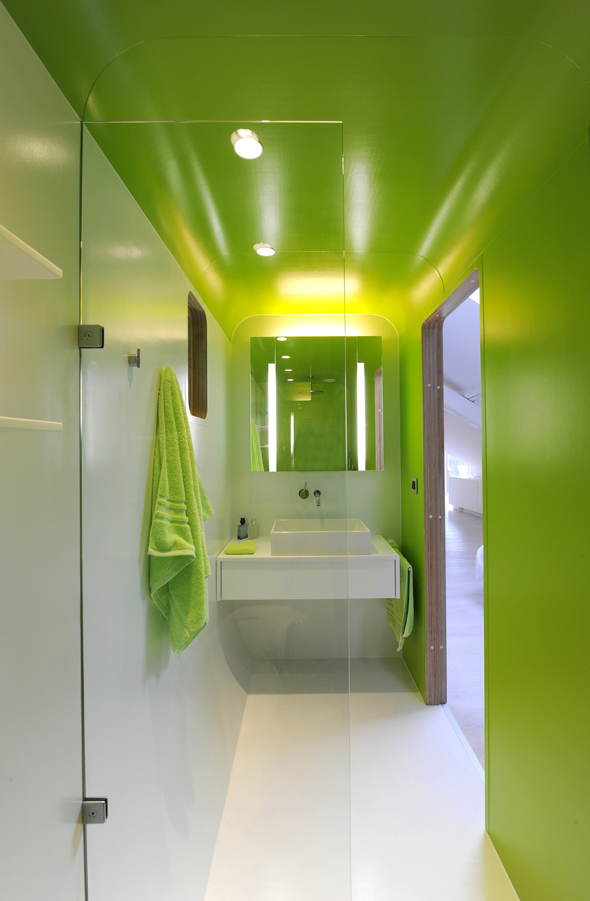 This bright green bathroom design incorporates a curved ceiling profile, turning the narrow room proportions into a positive feature.