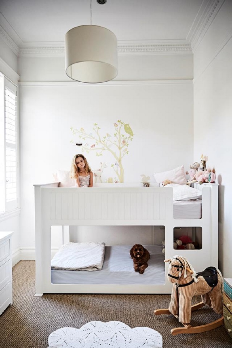 In this kid's room in a fashionista's federation-style home, a bunk bed frees up floor space for toys and activities. The decorated room allows unique toys, like the rocking horse and a wall decal, to add interest.