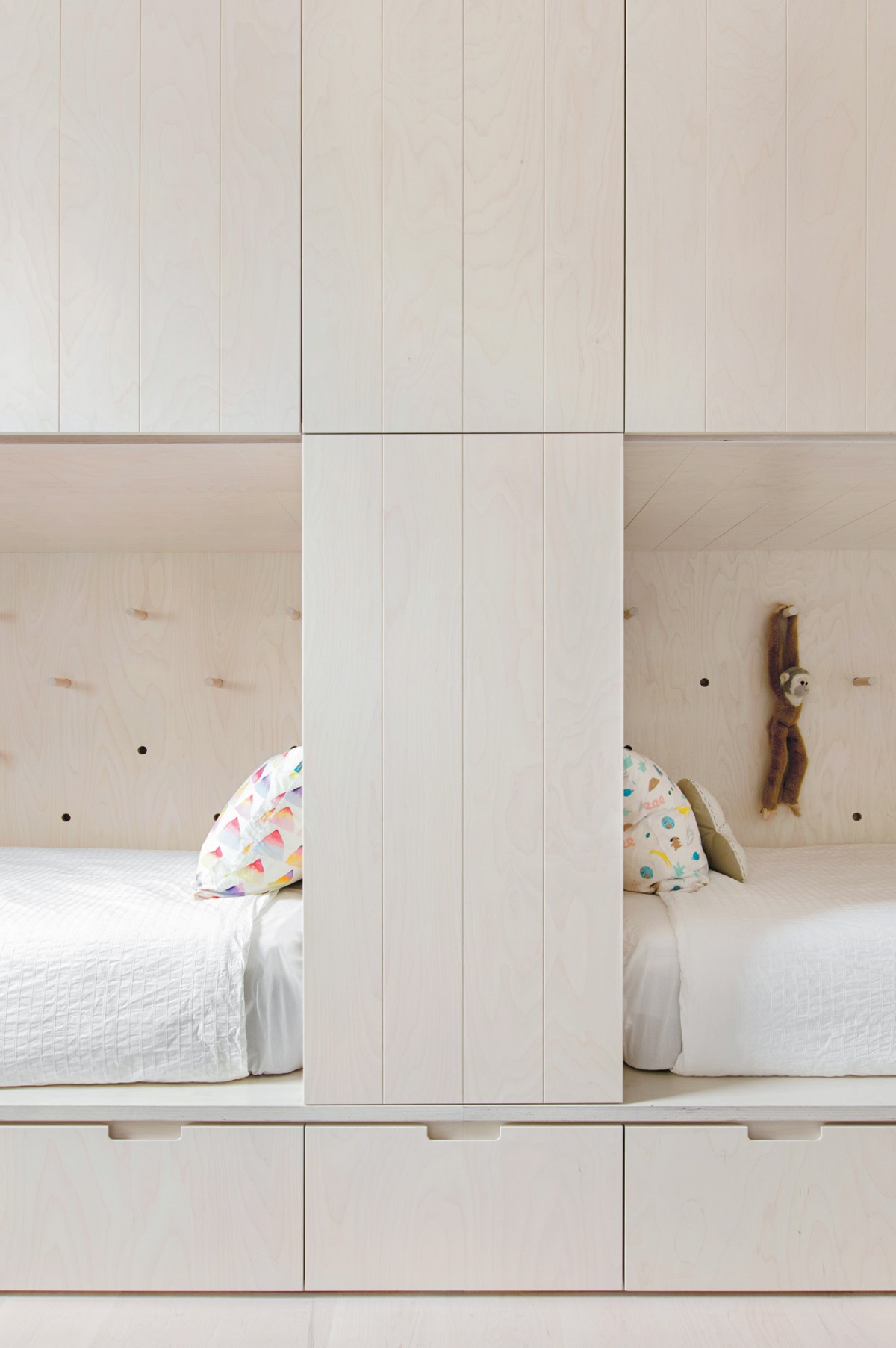 In this Scandinavian-inspired home, beds are encased in custom joinery, creating a bunk-bed effect. "It relieves the amount of loose furniture required leading the space to feel less cluttered and more spacious," says architect Clare Cousins.