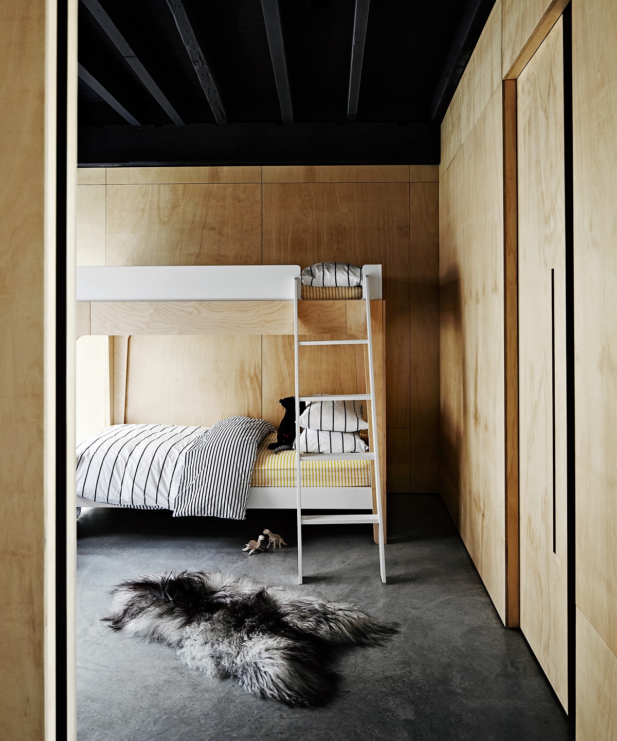 At the former home of comedian Merrick Watts, heated polished concrete floors and a sheepskin rug created a super cozy kid's room. The bunk bed is decorated with bedlinen from Unison.